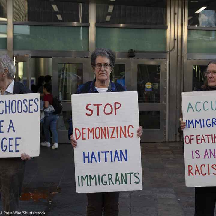 Anti-demonization of immigrants demonstrators hold signs that reads 'NO ONE CHOOSES TO BE A REFUGEE' 'STOP DEMONIZING HAITIAN IMMIGRANTS' 'ACCUSING IMMIGRANTS OF EATING PETS IS AN OLD RACIST LIE.