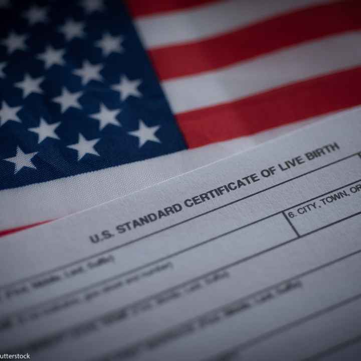 A birth certificate in front of an American flag.